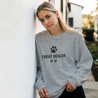 Load image into Gallery viewer, Ash - Treat Dealer sweatshirt, worn by a woman leaning on a white wall
