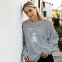 Load image into Gallery viewer, Graphite Heather - Dog Spelled Backwards Is God sweatshirt, worn by a woman leaning on a white wall
