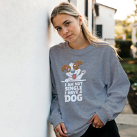 Load image into Gallery viewer, Graphite Heather - I Am Not Single I Have A Dog sweatshirt, worn by a woman leaning on a white wall
