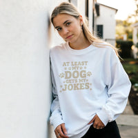 Load image into Gallery viewer, White - At Least My Dog Gets My Jokes sweatshirt, worn by a woman leaning on a white wall
