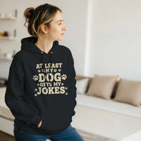 Load image into Gallery viewer, Black - At Least My Dog Gets My Jokes hoodie, worn by a woman sitting on a couch in a living room
