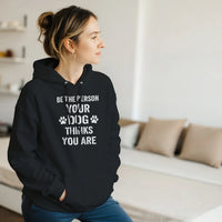 Load image into Gallery viewer, Black - Be The Person Your Dog Thinks You Are hoodie, worn by a woman sitting on a couch in a living room
